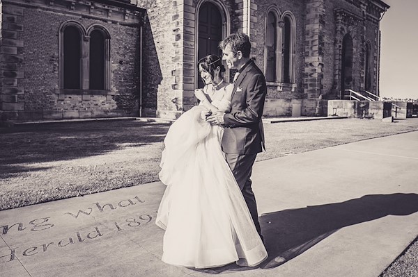 Danielle and Andrew together on Newcastle harbour at golden hour — a real Newcastle harbour wedding at Newcastle Cruising Yacht Club photographed by John Adams