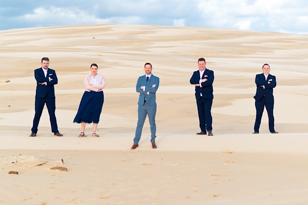 Tina and Stephen together on the Anna Bay sand dunes at Port Stephens, the soft dune ridges and spring sky behind them
