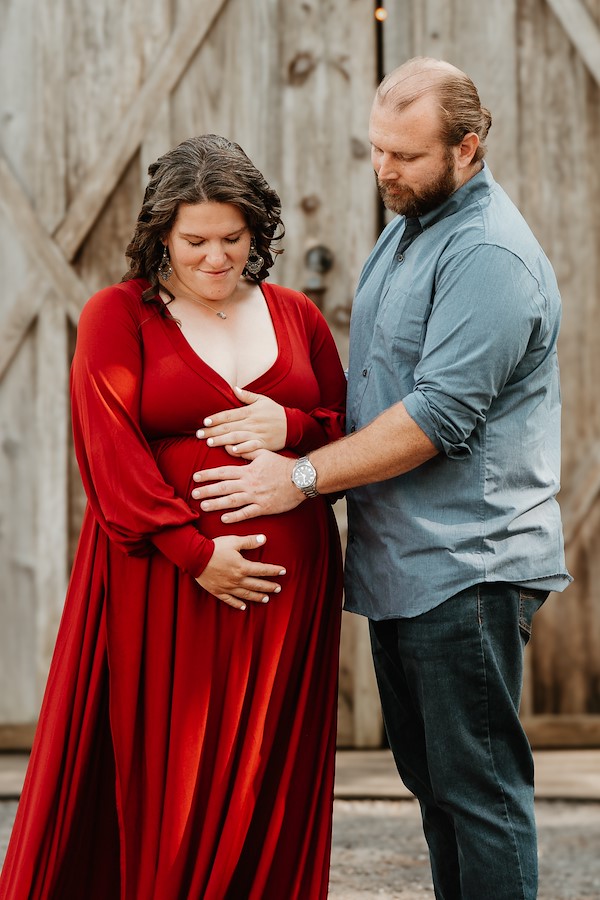 Mom and dad touching belly and smiling at Rustic Ridge, Deridder Louisiana